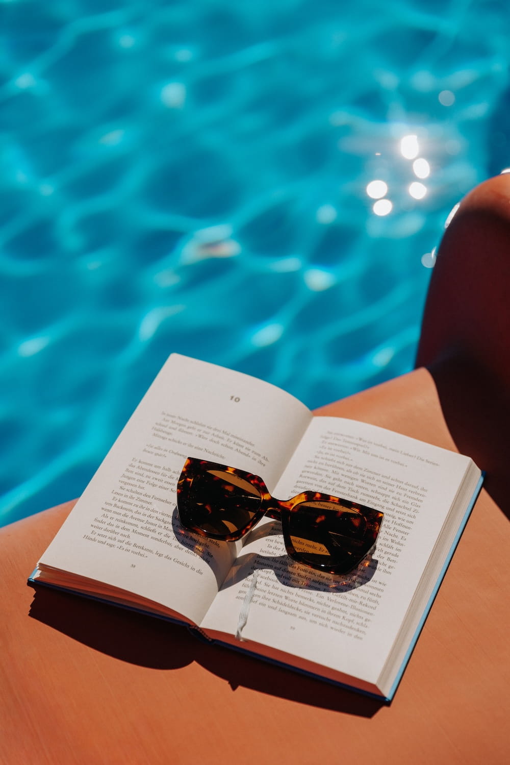 Buch und Sonnenbrille auf der Liege